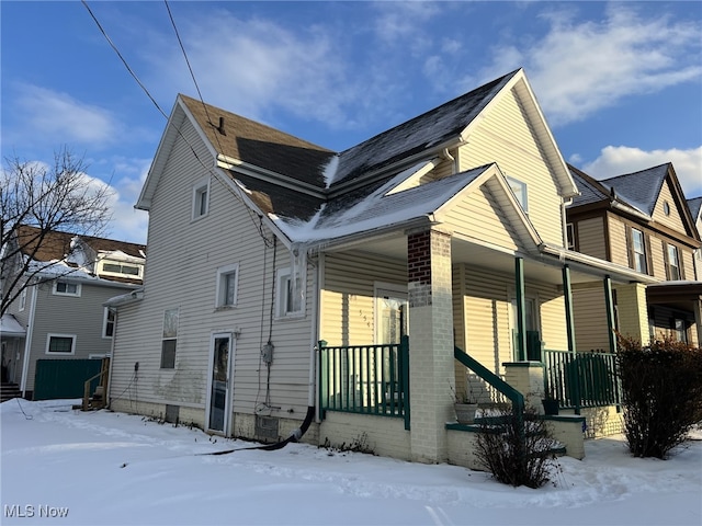 view of snow covered exterior with a porch and cooling unit