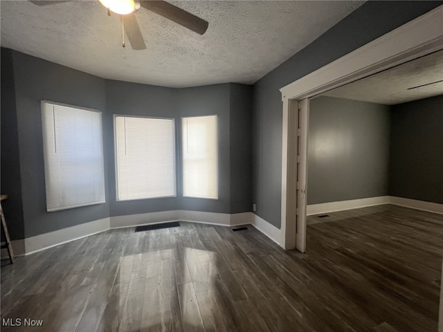 empty room with ceiling fan, dark hardwood / wood-style floors, and a textured ceiling