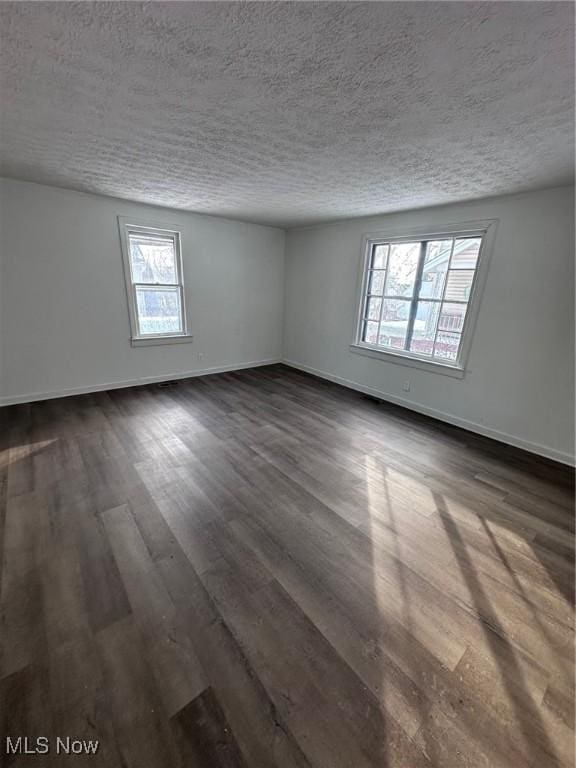 spare room featuring a textured ceiling and dark hardwood / wood-style flooring