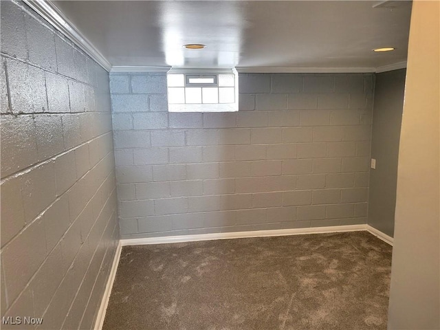 basement with ornamental molding, brick wall, and dark colored carpet