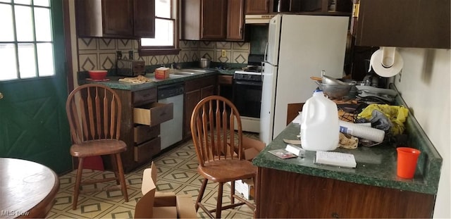 kitchen featuring dark brown cabinetry, sink, backsplash, and white appliances