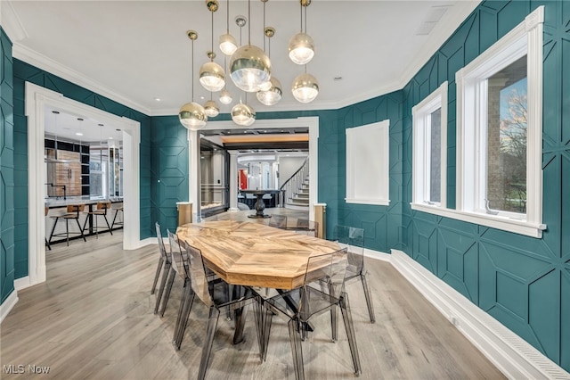 dining room with crown molding and light hardwood / wood-style flooring