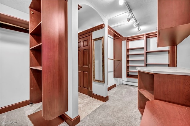 spacious closet featuring light colored carpet and baseboard heating