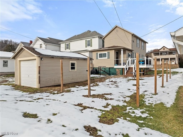 snow covered property with an outbuilding, a garage, and a deck