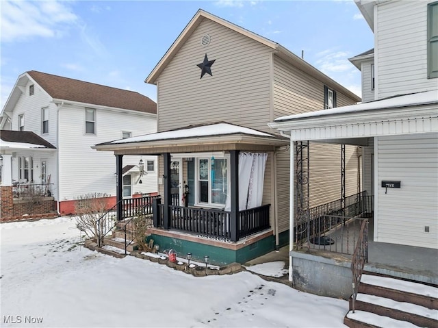 snow covered back of property featuring a porch