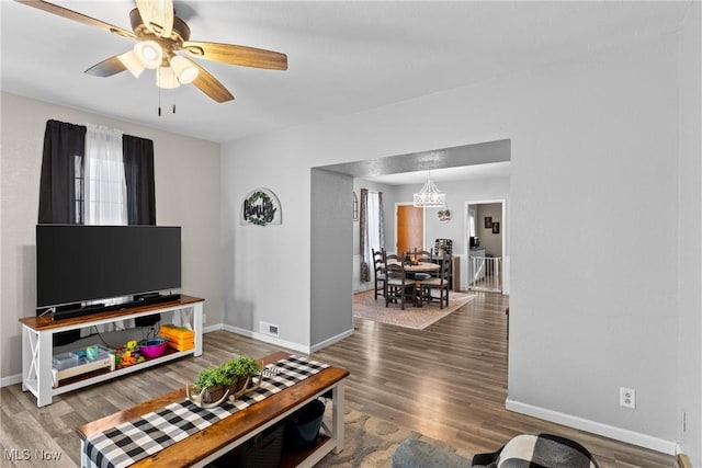 living room with hardwood / wood-style floors and ceiling fan with notable chandelier