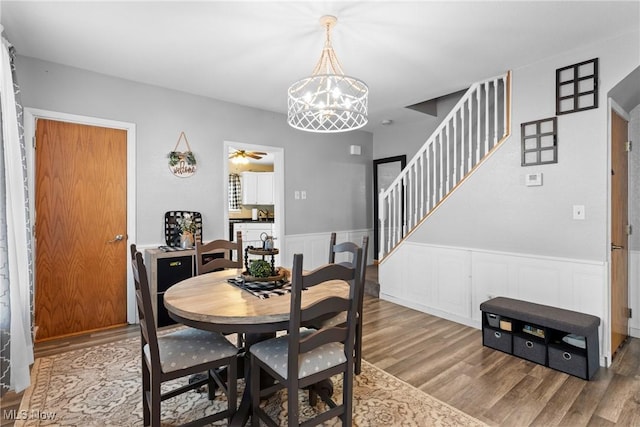 dining space featuring ceiling fan with notable chandelier and wood-type flooring