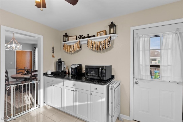 kitchen featuring light tile patterned flooring, decorative light fixtures, white cabinetry, dark stone counters, and ceiling fan