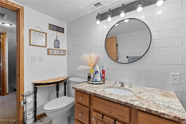 bathroom featuring tasteful backsplash, vanity, toilet, and tile walls