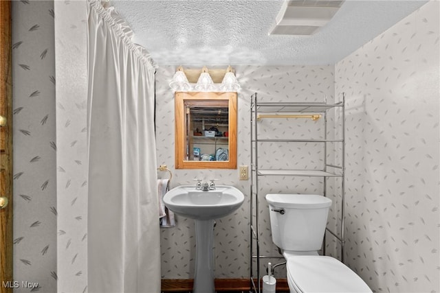 bathroom with sink, toilet, and a textured ceiling