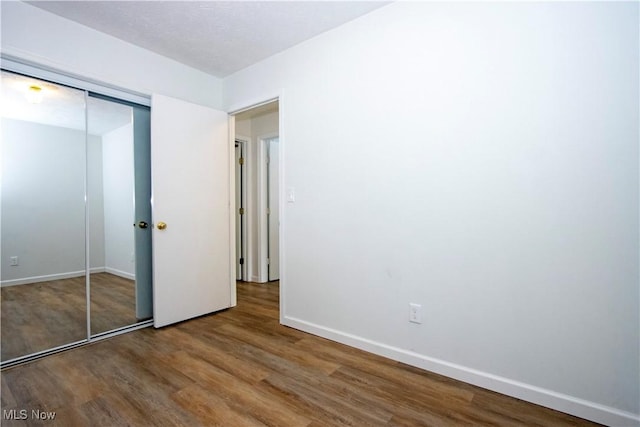 unfurnished bedroom featuring a closet, baseboards, and wood finished floors