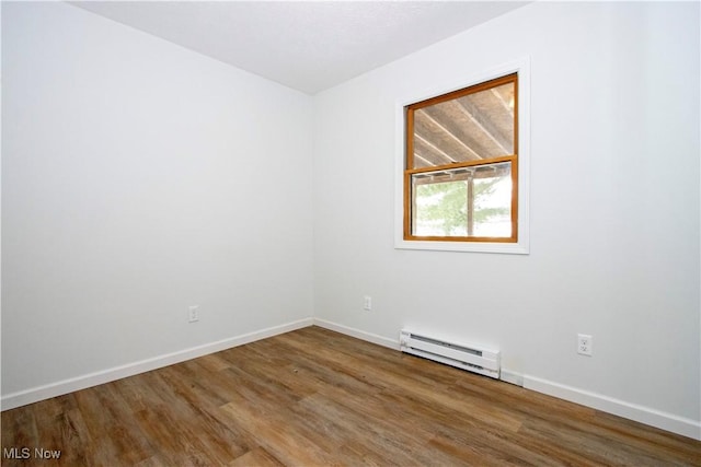 spare room featuring baseboards, baseboard heating, and wood finished floors