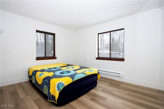 bedroom with baseboards, baseboard heating, and wood finished floors