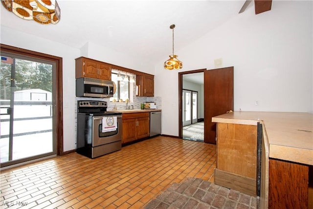 kitchen featuring decorative light fixtures, light countertops, backsplash, appliances with stainless steel finishes, and brown cabinetry