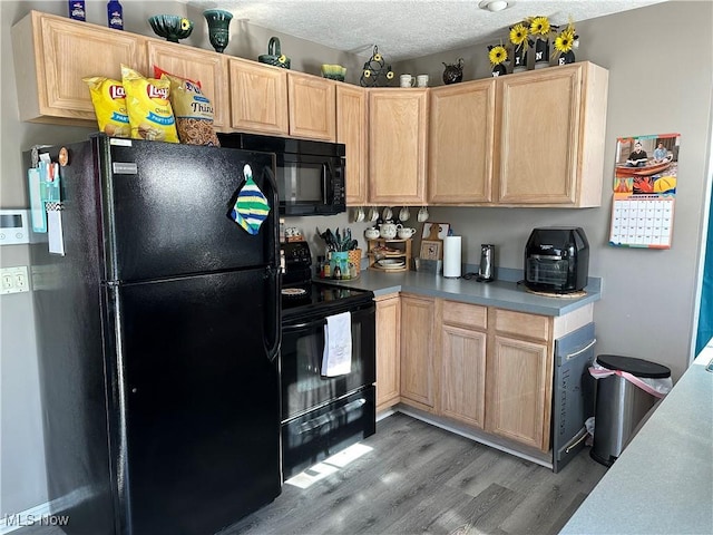 kitchen featuring wood-type flooring, light brown cabinetry, a textured ceiling, and black appliances