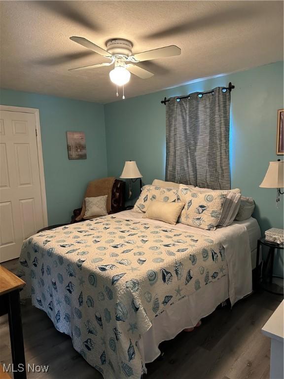 bedroom with hardwood / wood-style flooring, a textured ceiling, and ceiling fan