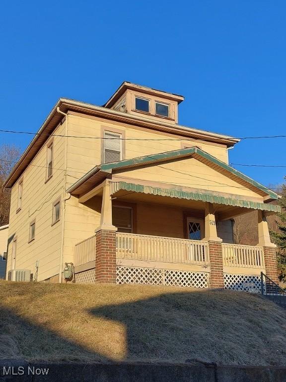 view of side of property featuring a lawn and covered porch