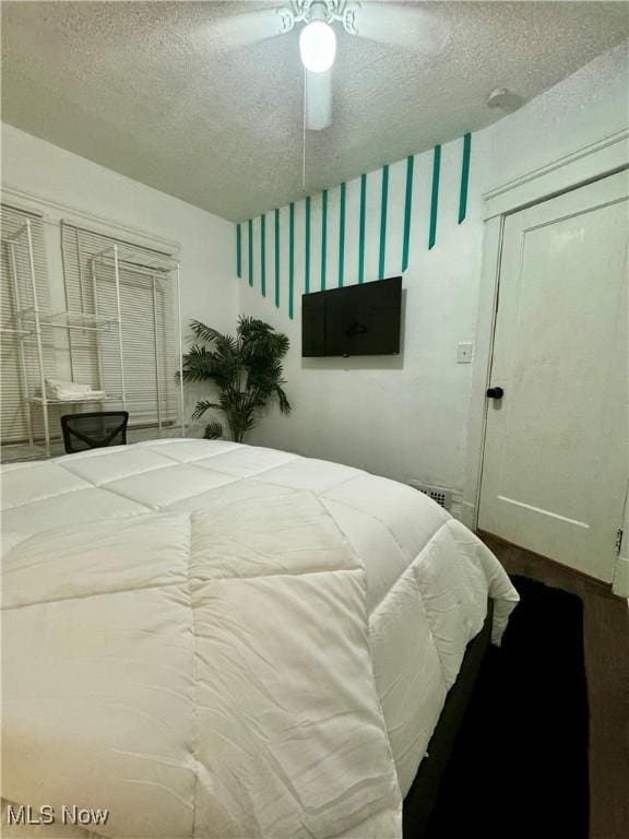 bedroom with a textured ceiling, ceiling fan, and a closet