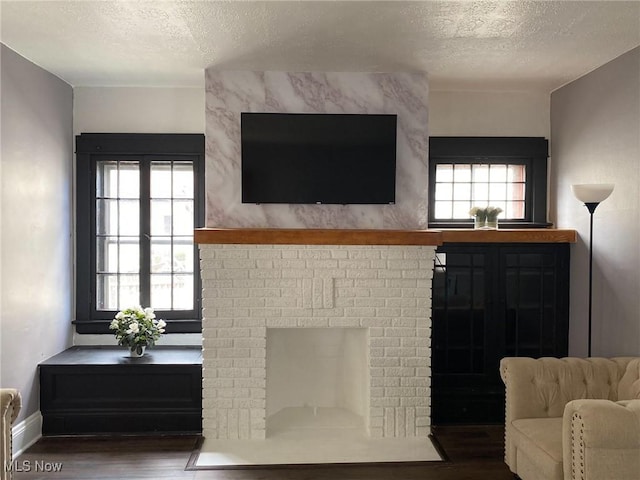 living room with dark hardwood / wood-style flooring, a brick fireplace, and a textured ceiling