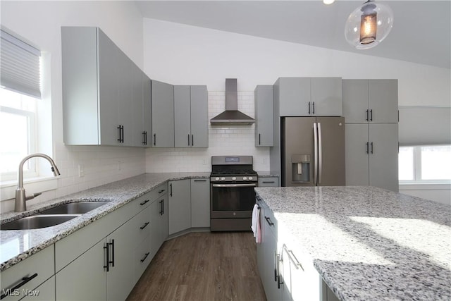 kitchen with light stone countertops, appliances with stainless steel finishes, sink, and wall chimney exhaust hood