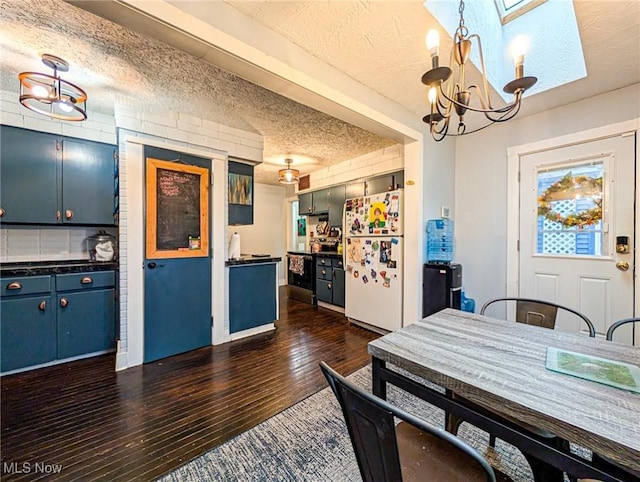 dining area featuring dark wood-type flooring, a skylight, a chandelier, and a textured ceiling