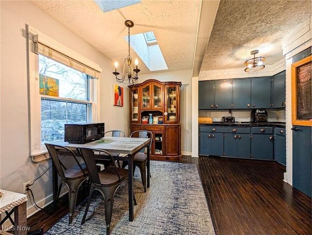 dining area with dark hardwood / wood-style flooring, a skylight, a chandelier, and a textured ceiling