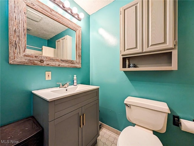 bathroom featuring vanity, a textured ceiling, and toilet