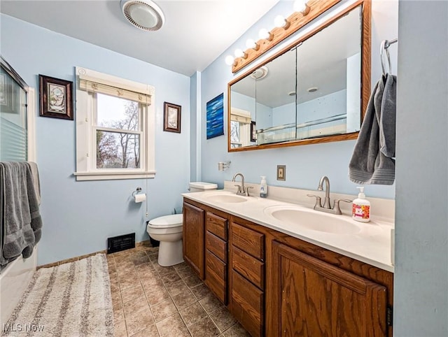 bathroom featuring vanity, toilet, and a shower with shower door