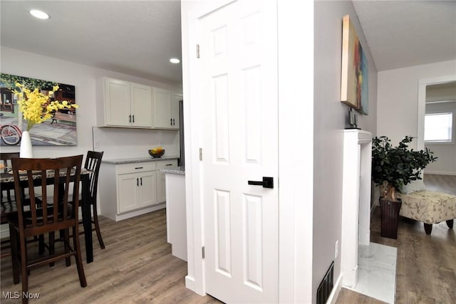 interior space featuring light stone countertops, white cabinets, and light wood-type flooring