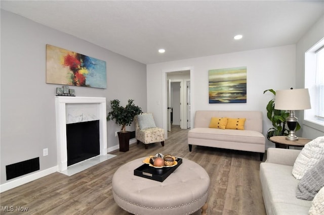 living room with a high end fireplace, visible vents, baseboards, recessed lighting, and wood finished floors