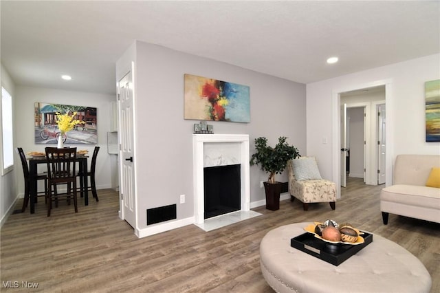 living area featuring recessed lighting, wood finished floors, baseboards, and a premium fireplace