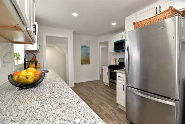 kitchen with a sink, wood finished floors, white cabinetry, recessed lighting, and appliances with stainless steel finishes