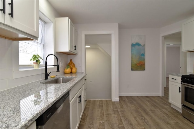 kitchen featuring light stone countertops, light wood-style floors, appliances with stainless steel finishes, and a sink