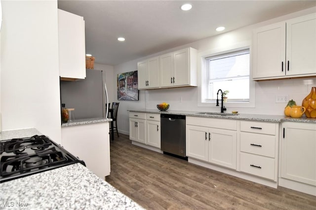 kitchen with a sink, wood finished floors, white cabinetry, appliances with stainless steel finishes, and decorative backsplash