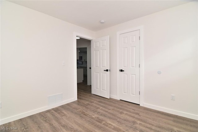 unfurnished bedroom featuring visible vents, baseboards, and wood finished floors