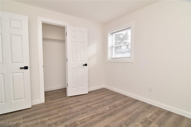 unfurnished bedroom with a closet, baseboards, and wood finished floors