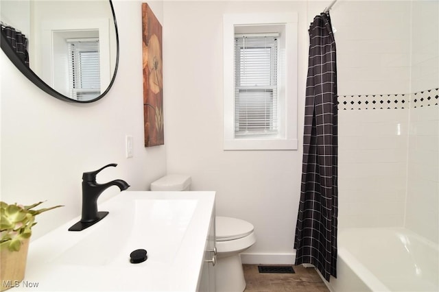 bathroom featuring visible vents, toilet, wood finished floors, shower / tub combo, and vanity