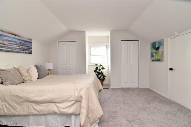 bedroom featuring vaulted ceiling, baseboards, multiple closets, and carpet floors