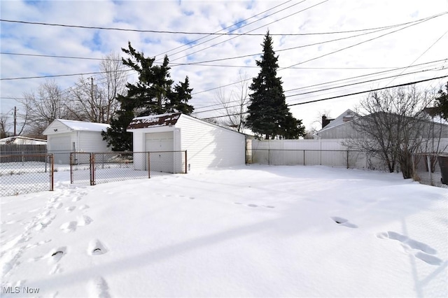 yard layered in snow with a garage, an outbuilding, and fence