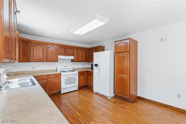 kitchen with white appliances, light hardwood / wood-style floors, and sink