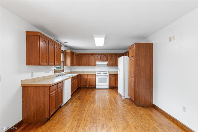 kitchen featuring white appliances, sink, and light hardwood / wood-style flooring