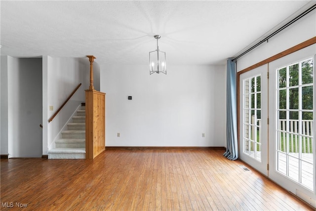 spare room with hardwood / wood-style flooring and a notable chandelier