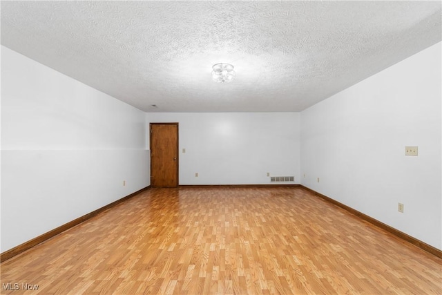 spare room with light wood-type flooring and a textured ceiling