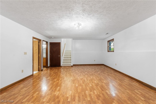 unfurnished room featuring a textured ceiling and light wood-type flooring