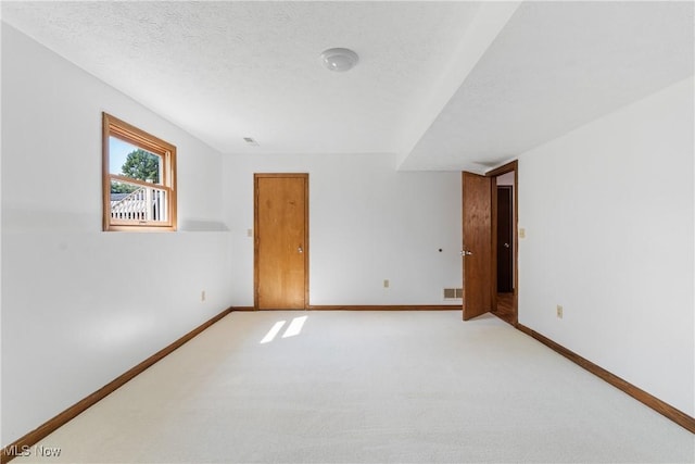 spare room with light colored carpet and a textured ceiling