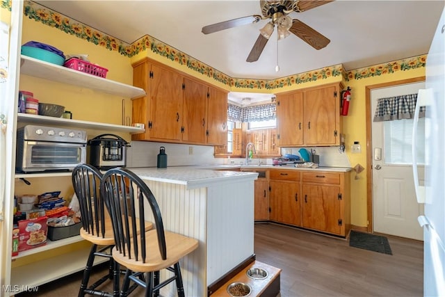 kitchen featuring hardwood / wood-style floors, sink, a kitchen breakfast bar, ceiling fan, and kitchen peninsula