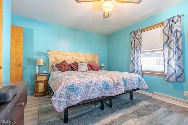 bedroom with a baseboard heating unit, wood-type flooring, and ceiling fan