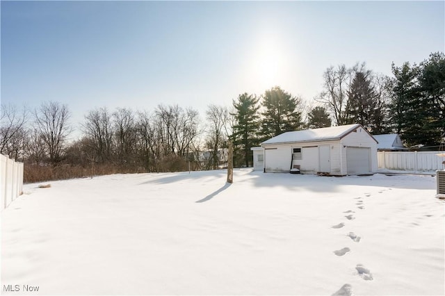 yard layered in snow with an outbuilding and a garage