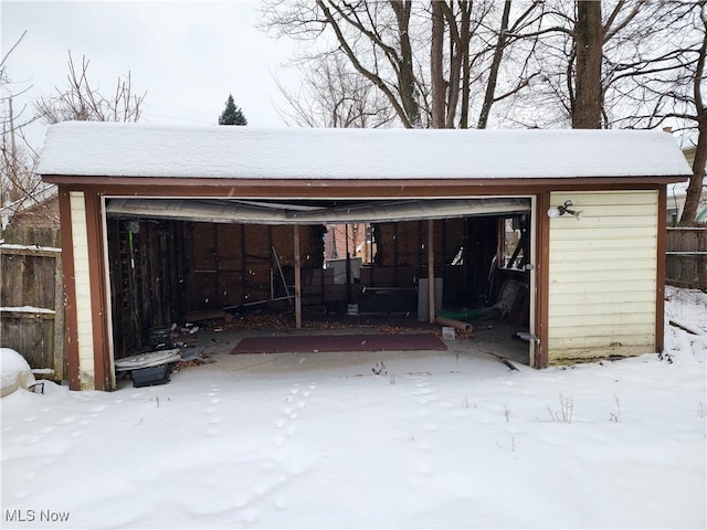 snow covered garage featuring fence