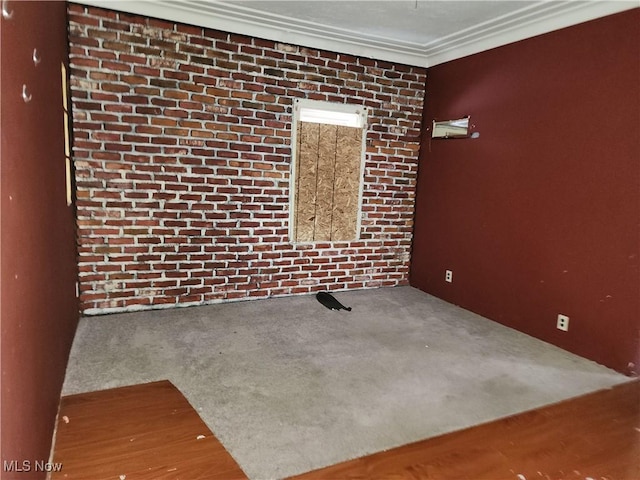 spare room featuring crown molding, brick wall, and carpet flooring